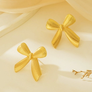 Detailed close-up of gold bow earrings with elegant vertical brushed texture and golden finish