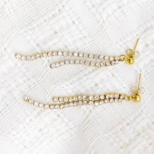 Detail view of gold tassel earrings featuring double wavy chains and sparkling zircons
