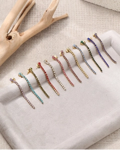 Détail macro de onze boucles d'oreilles colorées en strass avec de longues chaînes