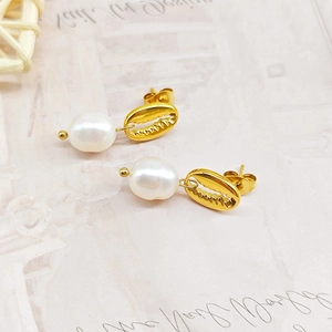 Gros plan de boucles d'oreilles coquillage dorées avec perles irisées et style océan