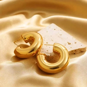 Modern chunky gold hoop earrings with polished mirror finish on a champagne silk background