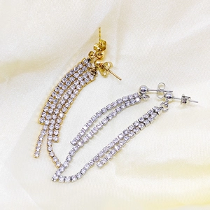 Close-up of gold and silver long tassel earrings with sparkling rows of zircon stones