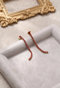 Détail de boucles d'oreilles pendantes à pompons avec zircons rouges élégants