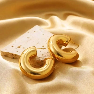 Detailed view of chunky 18K gold plated C-shaped hoop earrings on white stone