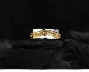 Macro shot of silver ring featuring golden wheat ear relief on polished metal surface