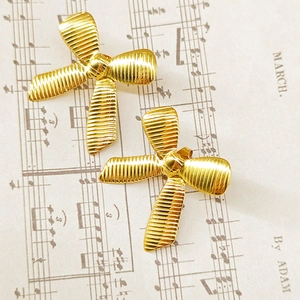 Macro detail of gold bow earrings with textured striped finish on musical notes