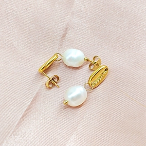 Détails macro de boucles d'oreilles perles baroques avec éléments coquillage doré