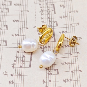 Élégantes boucles d'oreilles coquillage dorées avec perles blanches sur partition