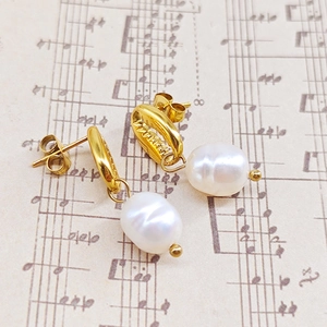Vue détaillée de boucles d'oreilles coquillage doré avec perles baroques sur partition