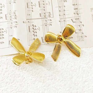 Macro detail of 18k gold plated stainless steel bow earrings with textured surface