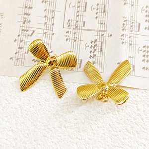 Detail shot of golden bow earrings with textured stripes on musical sheet background