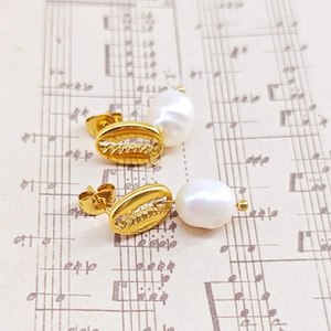 Détail macro de boucles d'oreilles coquillages dorés avec perles sur papier à musique vintage