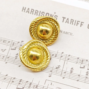 Macro detail of vintage 18K gold teardrop earrings with woven texture on retro paper
