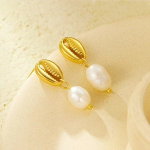 Détail de boucles d'oreilles coquillages dorés élégantes avec perles d'eau douce blanches