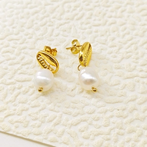 Détail de boucles d'oreilles bohèmes en coquillage doré avec perles blanches élégantes