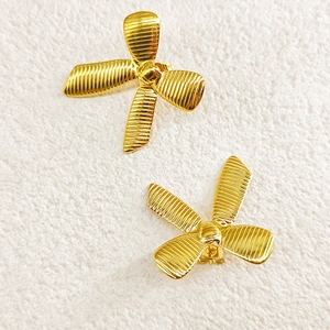 Detailed close-up of 18k gold plated bow earrings with unique textured ribbed finish