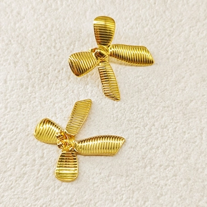 Detail of 18k gold plated bow earrings featuring horizontal pleated texture and studs