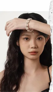 Detail of layered baroque pearl bracelet with floral spacers and heart charm on wrist
