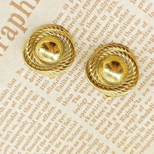 Detailed close-up of vintage golden dome earrings with intricate braided relief texture