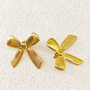 Detailed macro shot of 18k gold-plated bow stud earrings with textured stripe surface