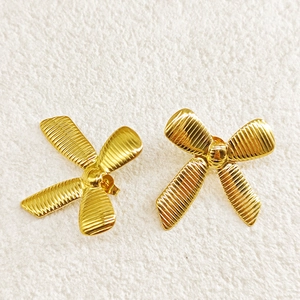 Detailed view of 18k gold plated stainless steel bow earrings with textured finish