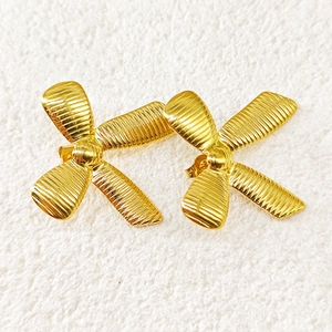 Detail of 18k gold plated bow earrings featuring elegant horizontal striped metal texture