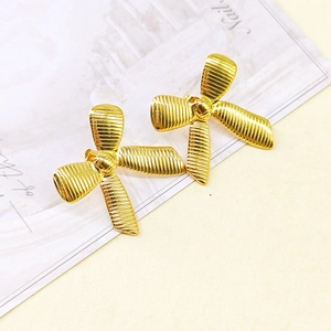Macro detail of 18k gold plated bow earrings featuring elegant ribbed metal texture