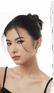 Close-up of elegant gold pearl drop earrings with minimalist silver hooks on model