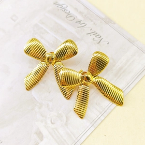 Detailed view of gold bow earrings featuring a textured horizontal stripe pattern