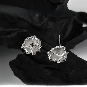 Macro detail of S925 sterling silver stud earrings with round white gemstones on charcoal