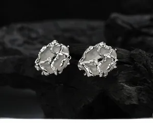 Macro detail of S925 silver stud earring with hand-wrapped liquid metal framing a gemstone