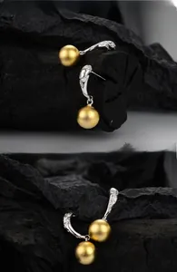 Detail of matte gold spherical drop earrings with sparkling silver-tone diamond studs