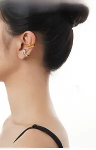Detail of gold wave and silver glitter ear cuff set worn in layered style on ear