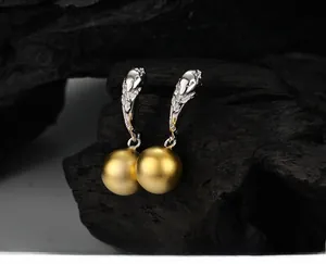 Macro detail of bicolored silver textured hooks and matte golden bead earrings