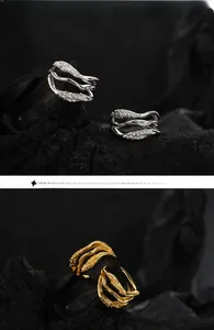 Macro detail of irregular wave texture rings in gold and silver finishes on black rock