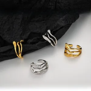 Close-up of irregular wave ear cuffs in gold and silver finish with textured details