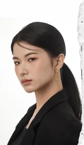 Detail view of long golden spiral wing earrings worn by model with professional black suit