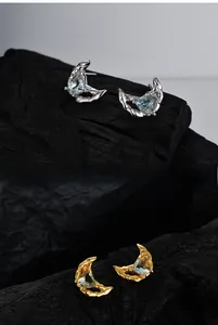 Détail de boucles d'oreilles lune texture lave avec pierres bleues en forme de cœur