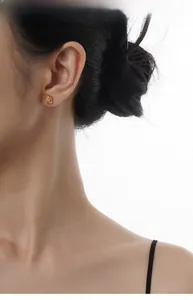 Close-up of golden S925 silver Saturn stud earring with white agate on model's ear