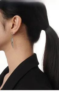 Detail of silver wing drop earrings in S925 sterling silver worn by a fashion model