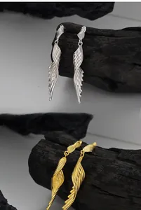 Macro shot of polished S925 sterling silver wing earrings in gold and silver finishes