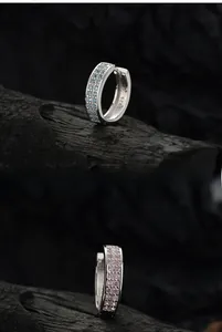 Vista macro di orecchini a cerchio in argento S925 con micro-pavé di gemme blu e rosa
