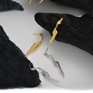 Detailed view of long S925 sterling silver wing earrings in gold and silver finishes