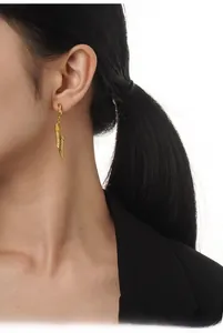 Detailed view of long gold spiral wing earrings on a model in a black suit