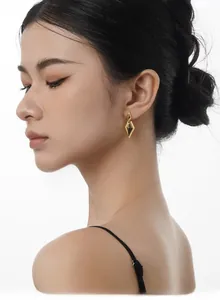 Polished gold double diamond geometric drop earrings worn by a model in minimalist style