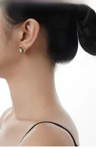 Detail view of ethnic S925 silver shell earring with gold twisted rope edge on ear