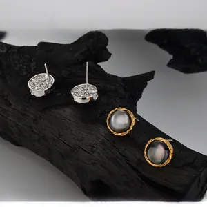 Macro view of S925 silver studs with gradient natural shell and hollow carved floral pattern