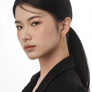 Elegant gold wing-shaped drop earrings with spiral texture worn by a fashion model