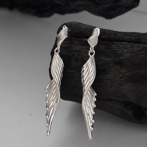 S925 sterling silver long wing earrings with a polished geometric twist design on wood