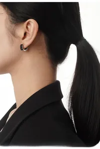 Detail of S925 silver ear buckle featuring baguette-cut black zircons worn by model